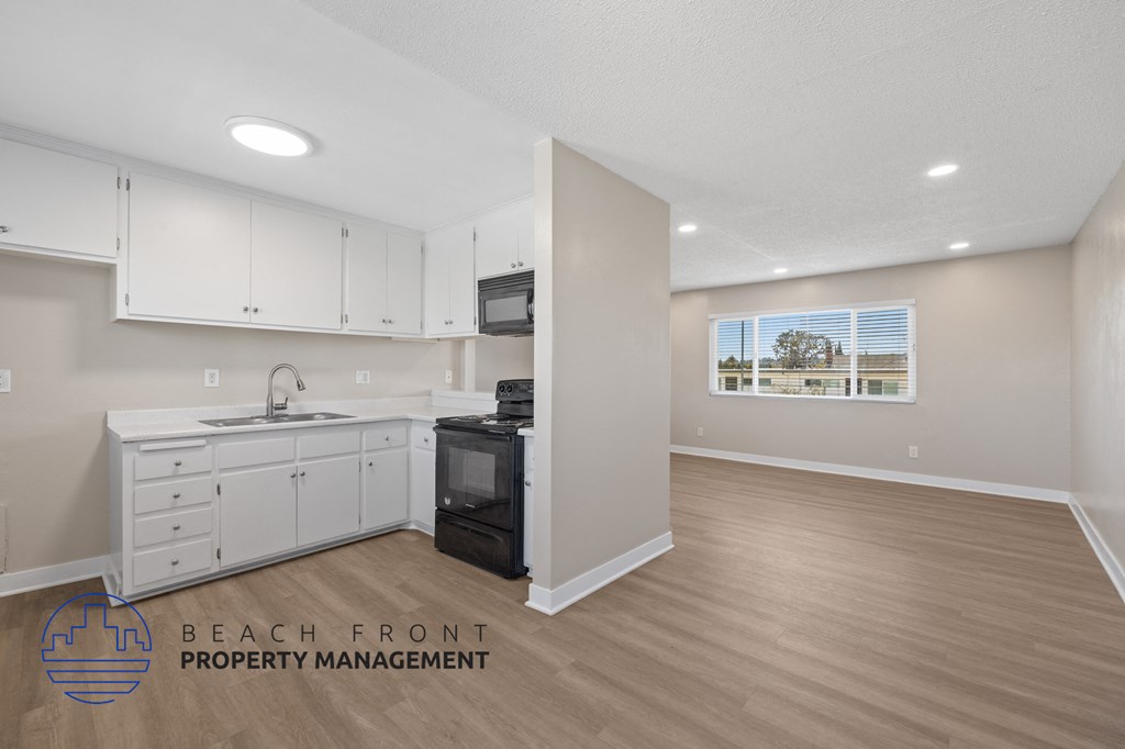 A kitchen with white cabinets and a black microwave.