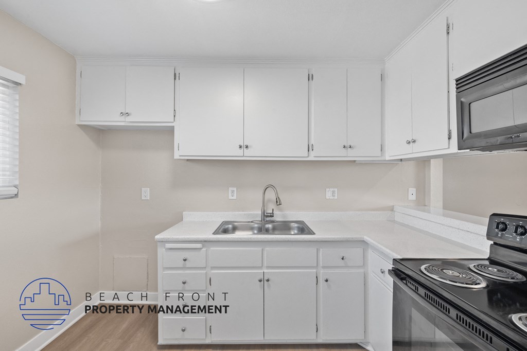 A kitchen with white cabinets and a stove top oven.