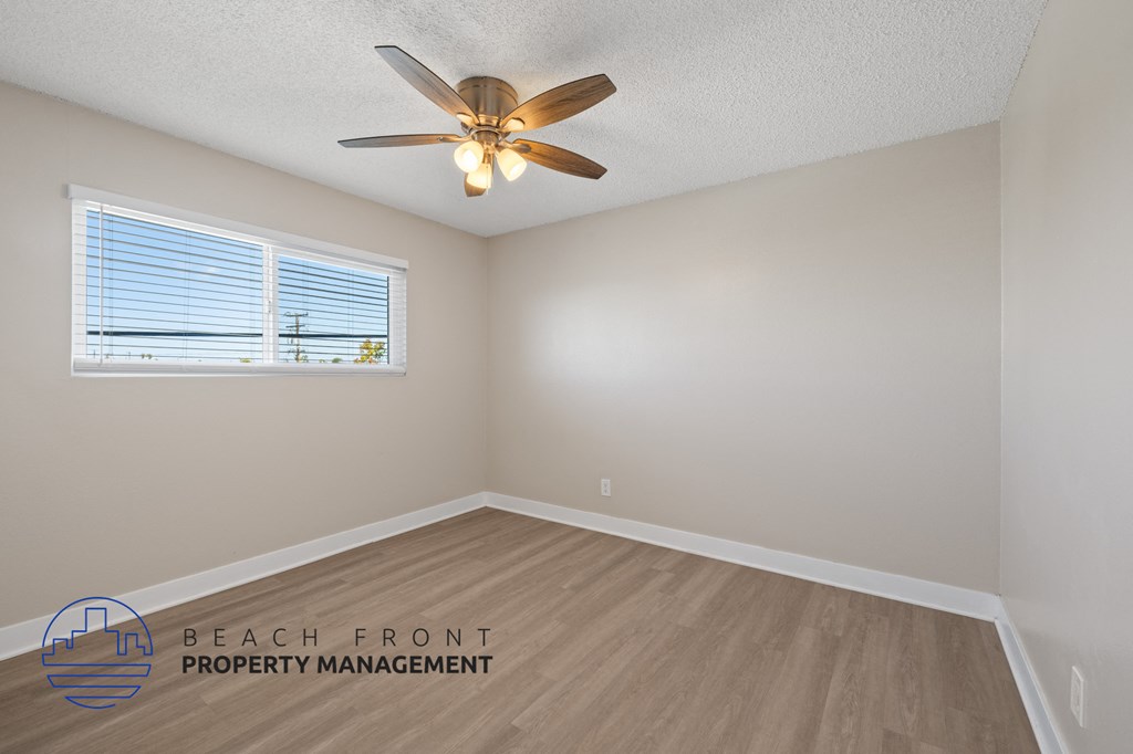 A room with a ceiling fan and a window with blinds.
