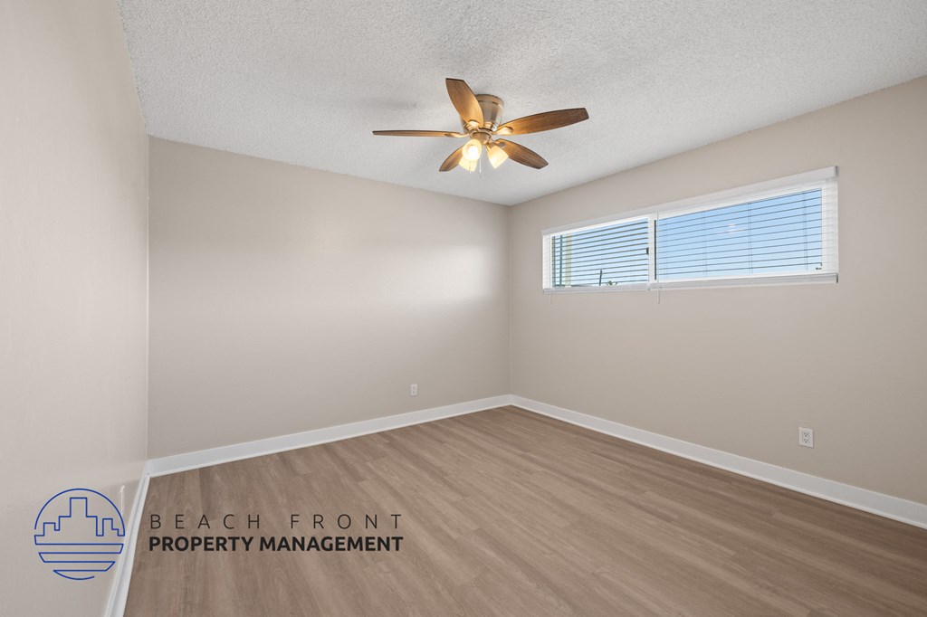 A room with a ceiling fan and a window with blinds.