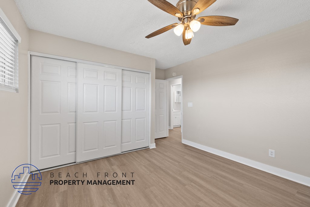 A room with a ceiling fan and a set of white doors.