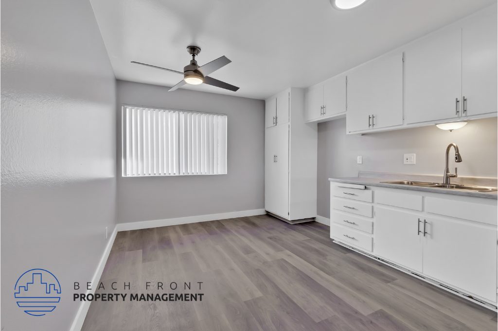 a kitchen with white cabinets and a sink and a ceiling fan