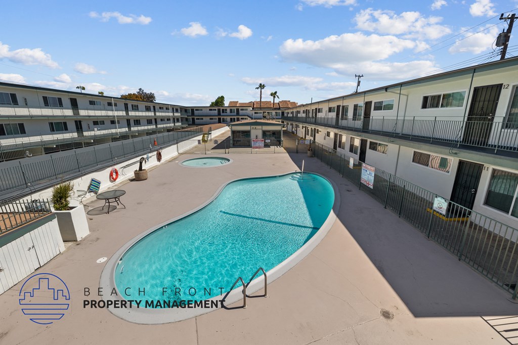 A swimming pool is surrounded by a fence and a sign that says Beach Front Property Management.