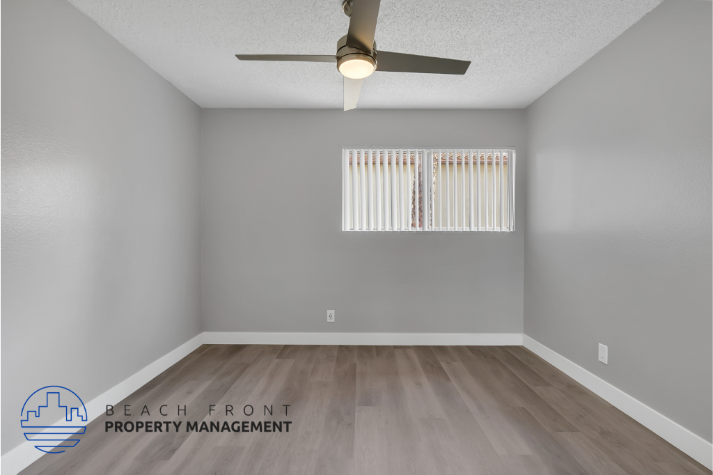 the renovated living room of an apartment with wood floors and a ceiling fan