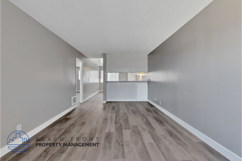 a renovated living room and kitchen with wood flooring and white walls