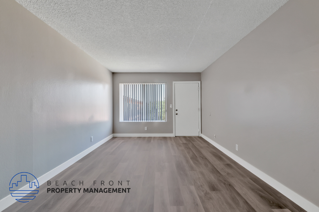 the upstairs living room of an apartment with wood flooring and a window