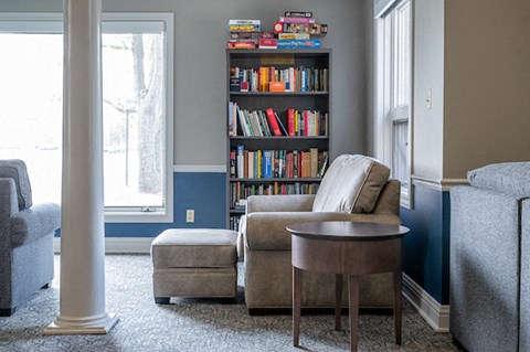 a living room with a chair and a table and a bookshelf