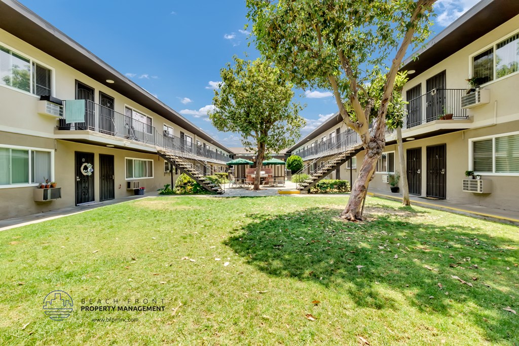 a courtyard with grass and trees at the whispering winds apartments in pearland, tx