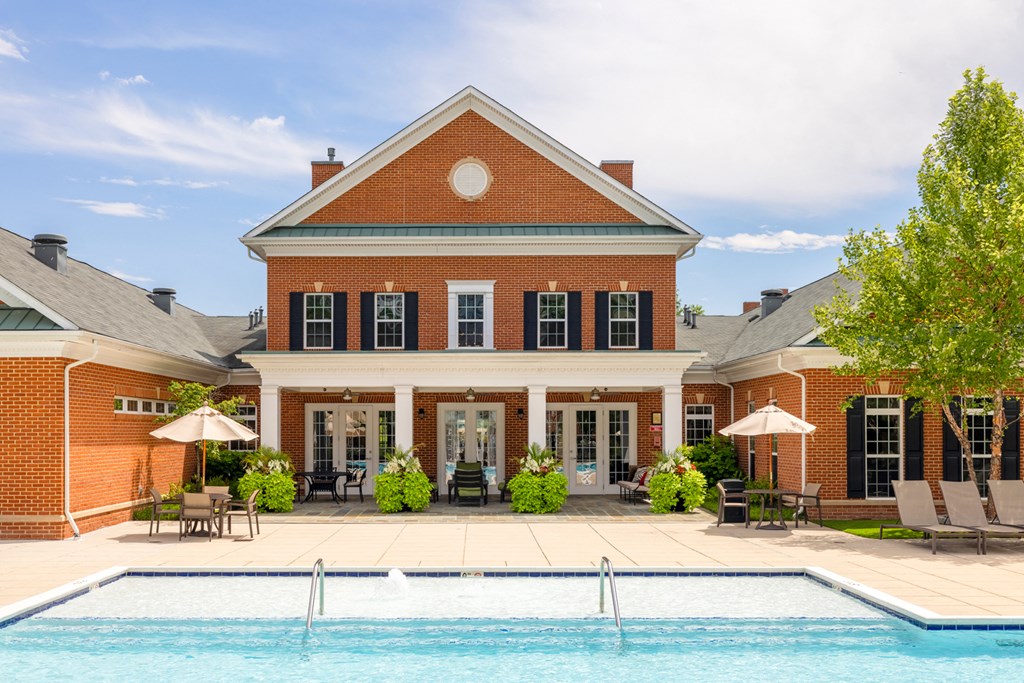 a swimming pool in front of a brick house with a pool