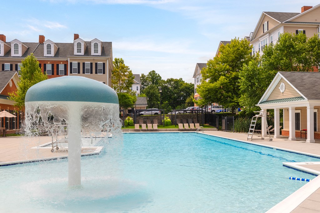 a large pool with a water fountain in front of a house