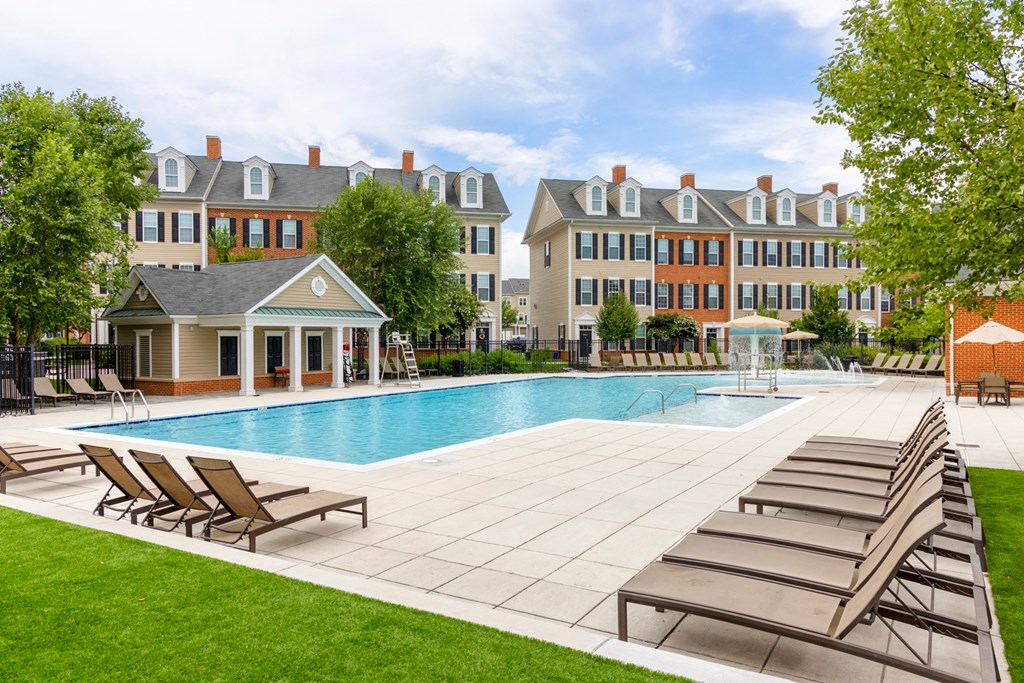 an outdoor swimming pool with lounge chairs and buildings in the background