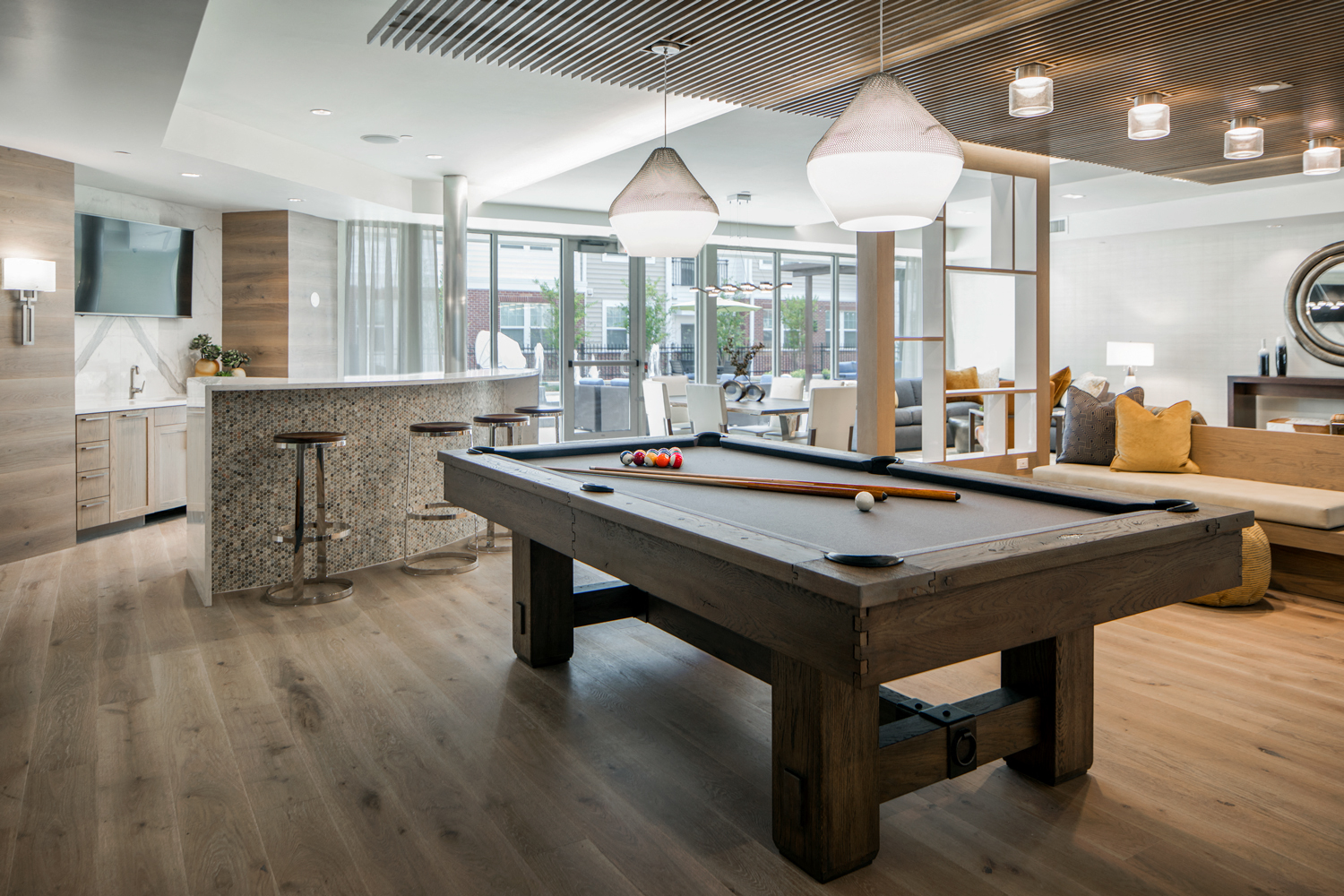 Community living room with plenty of comfortable seating, bar area for socializing, kitchen amenities, billiards table, and business area with available computers