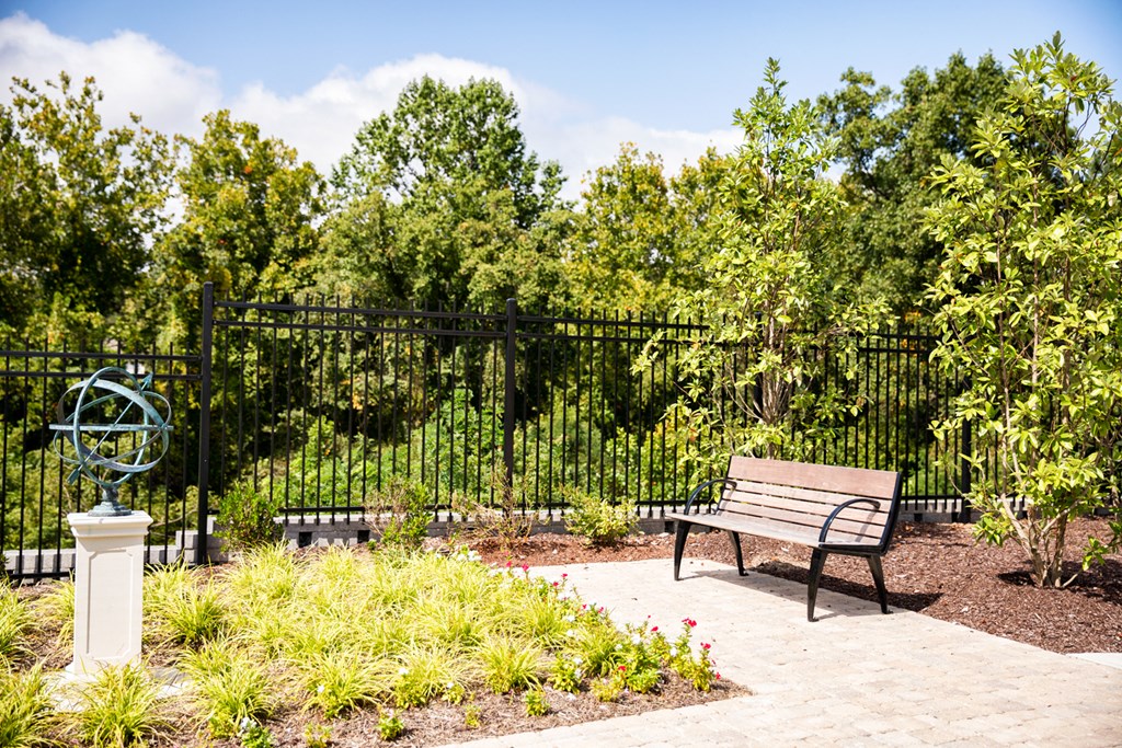 a park bench in front of a fence with trees