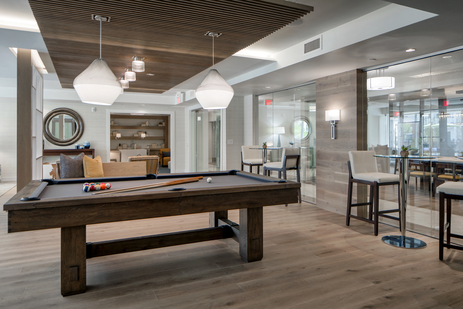 Community living room with plenty of comfortable seating, bar area for socializing, kitchen amenities, billiards table, and business area with available computers