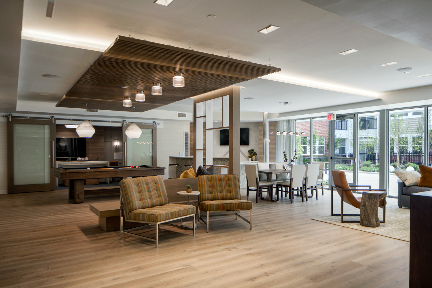 Community living room with plenty of comfortable seating, bar area for socializing, kitchen amenities, billiards table, and business area with available computers