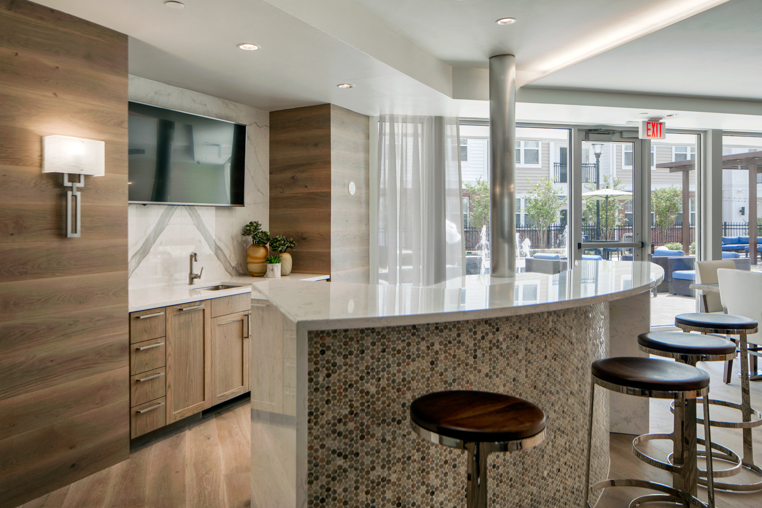 Community living room with plenty of comfortable seating, bar area for socializing, kitchen amenities, billiards table, and business area with available computers