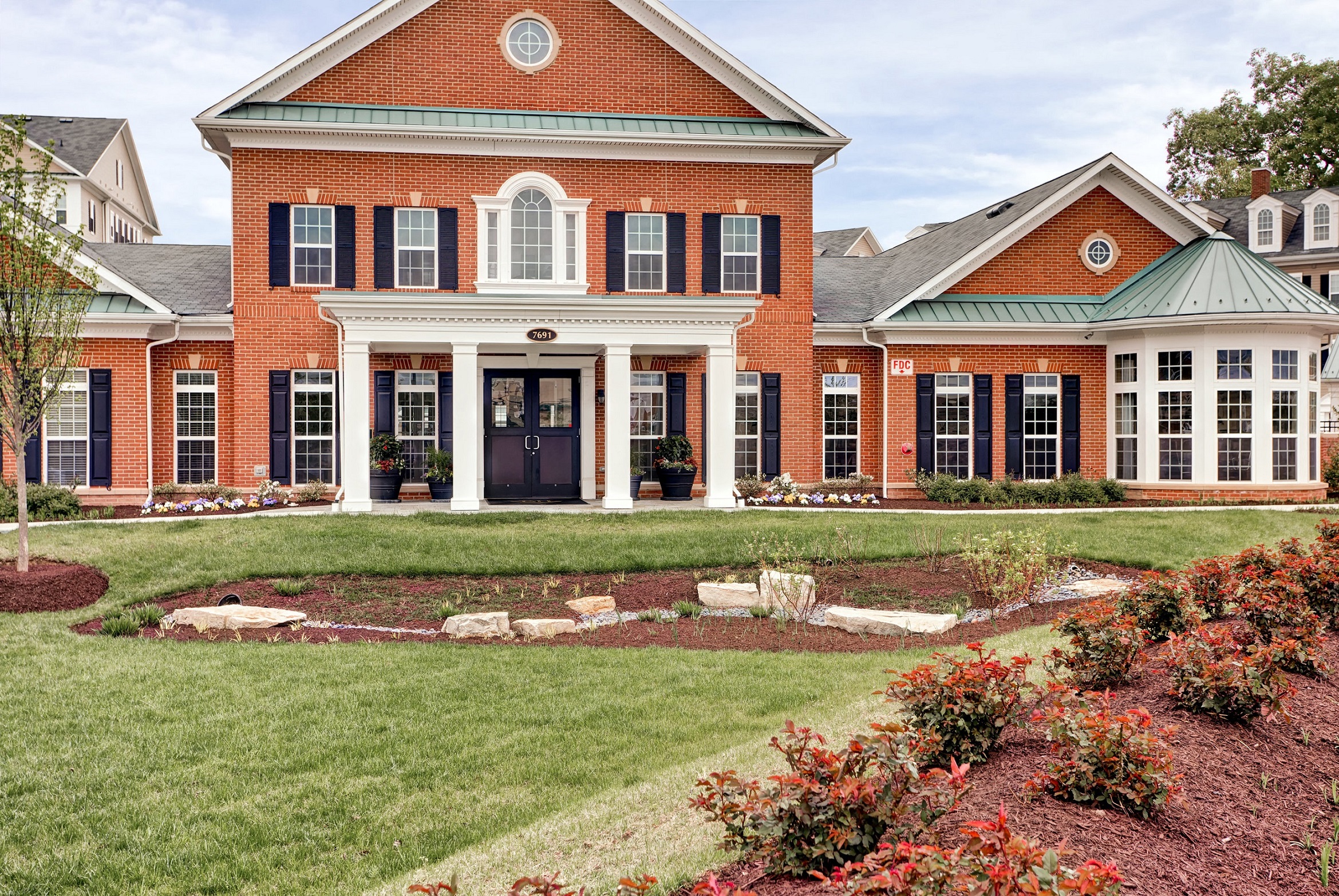 the front of a large brick house with a lawn and landscaping