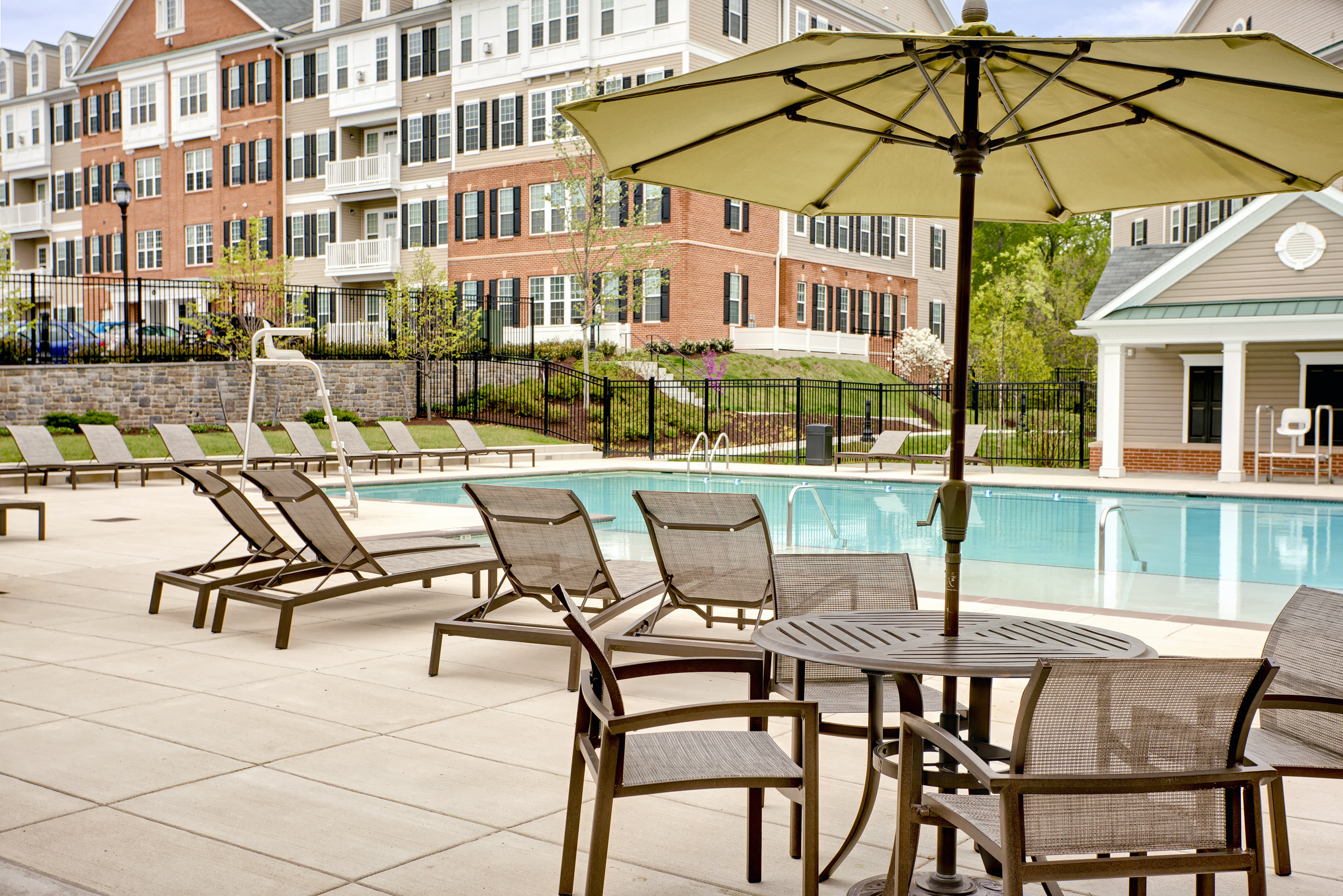 our apartments have a pool and a patio with chairs and an umbrella