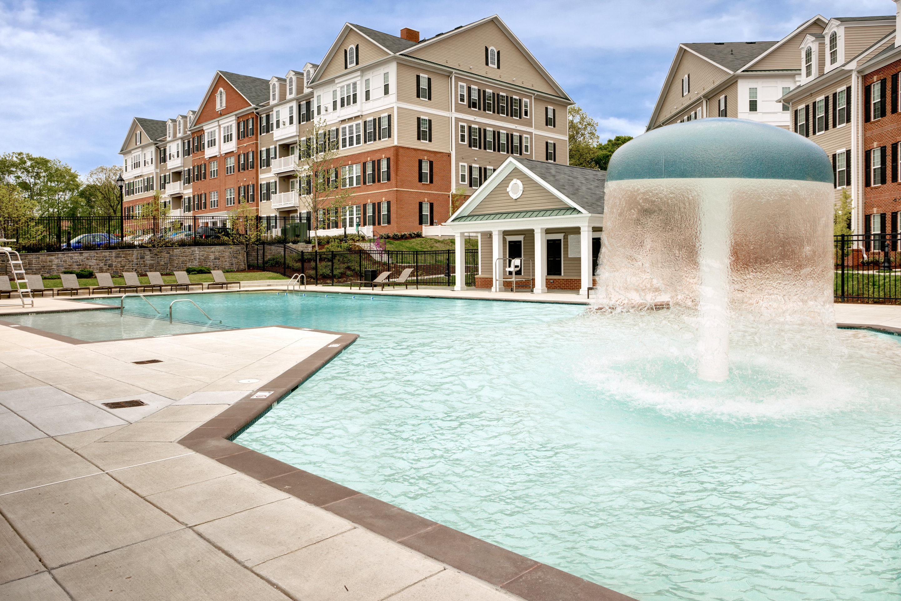 a pool with a fountain in front of an apartment building
