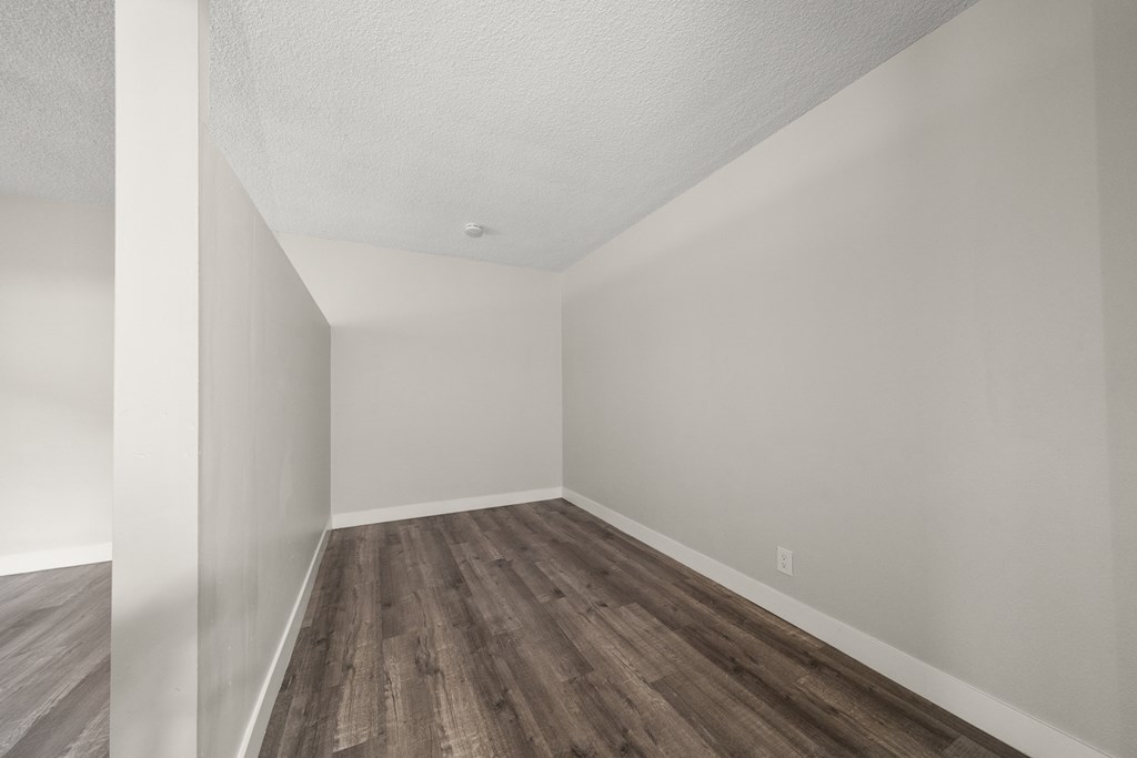an empty room with wood flooring and white walls