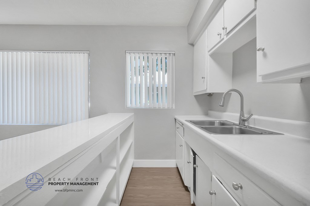 a white kitchen with white cabinets and a sink