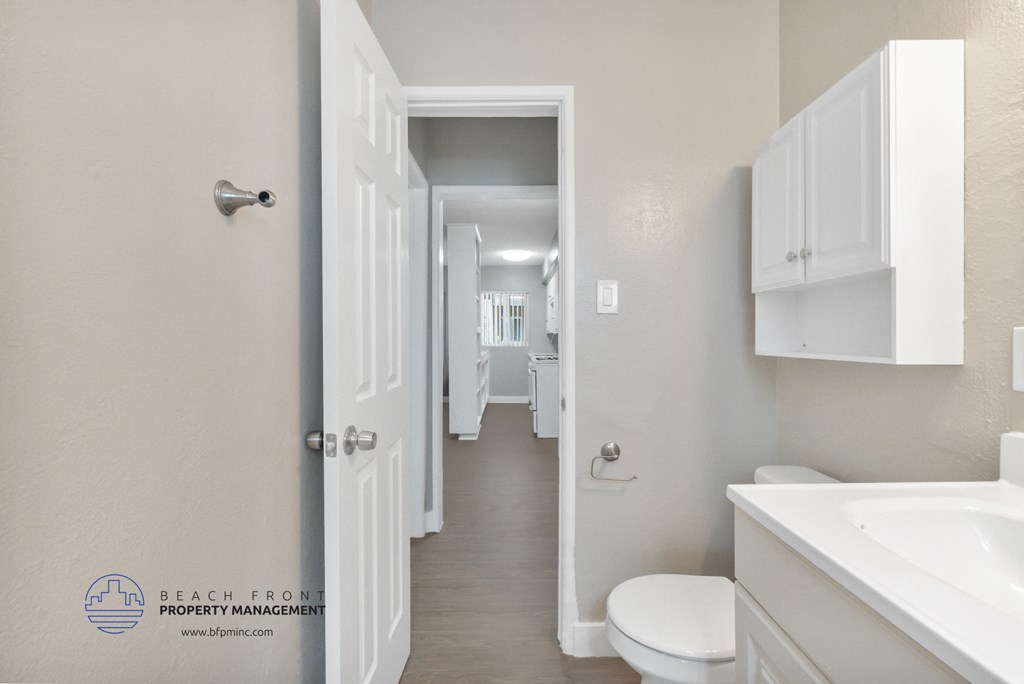 a white bathroom with white cabinets and a white toilet and sink