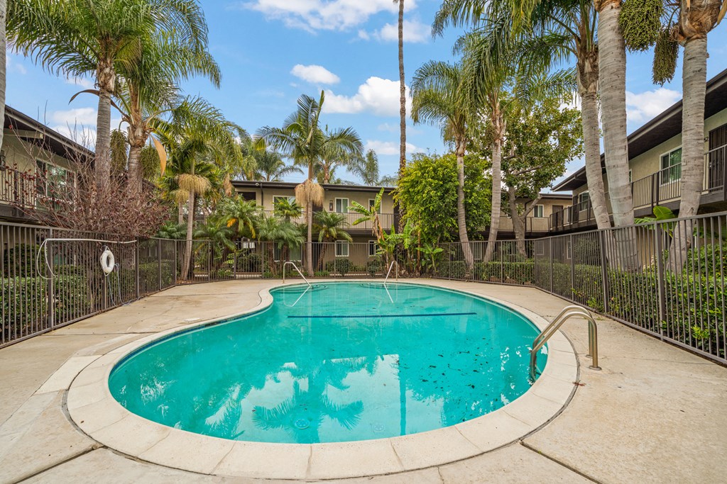 a swimming pool with palm trees and apartments in the background