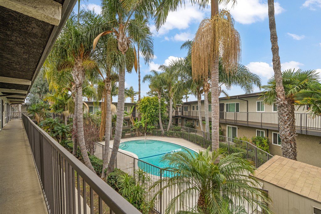 a balcony with a pool and palm trees