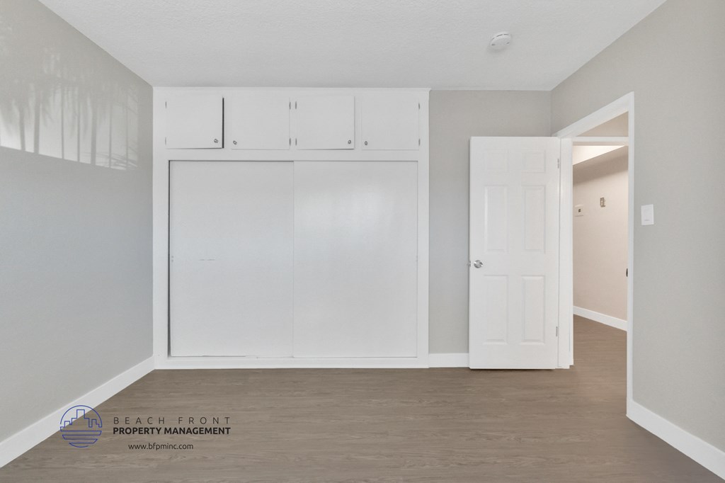 an empty room with white cabinets and a door to a closet