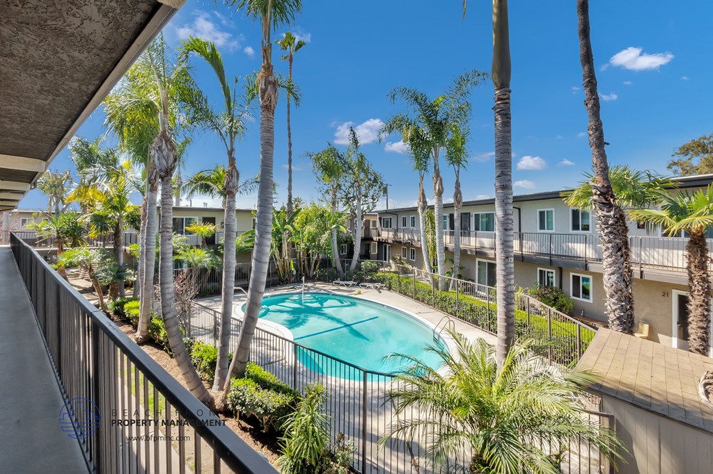 a swimming pool with palm trees and a building in the background