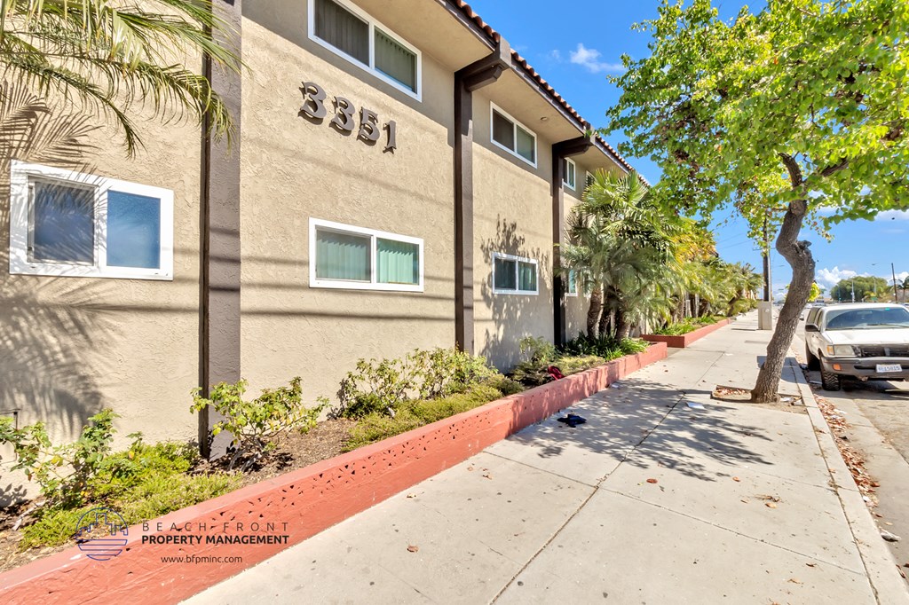 a sidewalk in front of a building with cars parked on the street