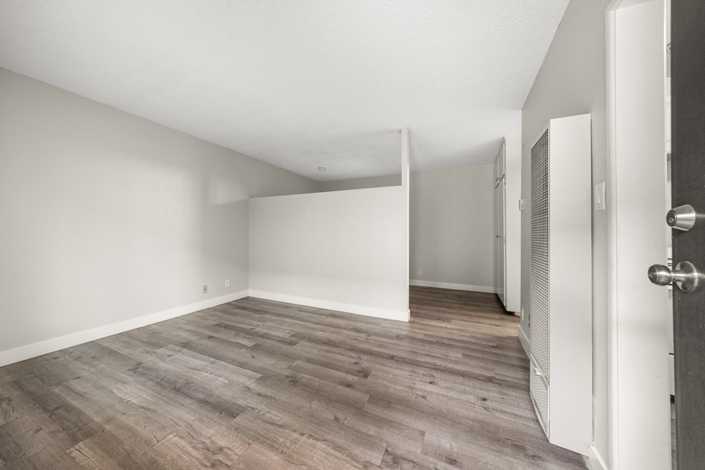 an empty living room with white walls and wood flooring