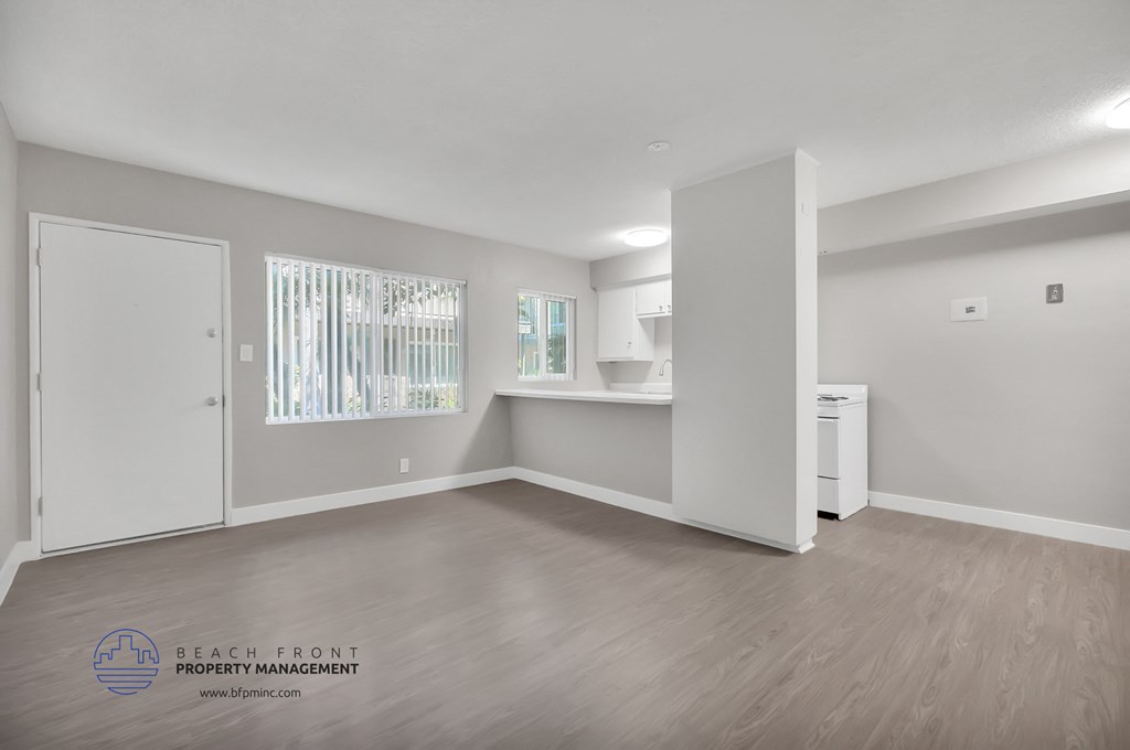 the living room and kitchen of a new home with white walls and wood flooring