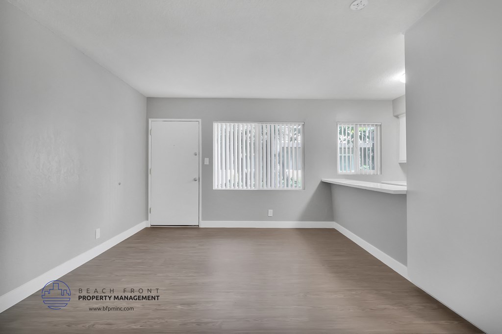 the living room of an apartment with wood floors and white walls
