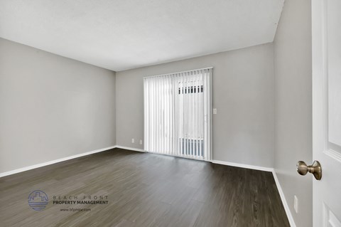the living room of an apartment with wood flooring and white walls