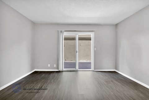 the living room of an empty apartment with wood flooring and a sliding glass door
