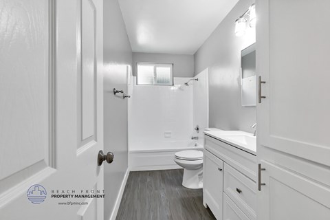 a white bathroom with white cabinets and a white toilet and sink