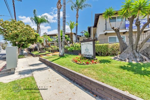 a sidewalk with a sign in the grass in front of a building