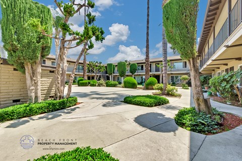 a courtyard with trees and bushes in front of a building