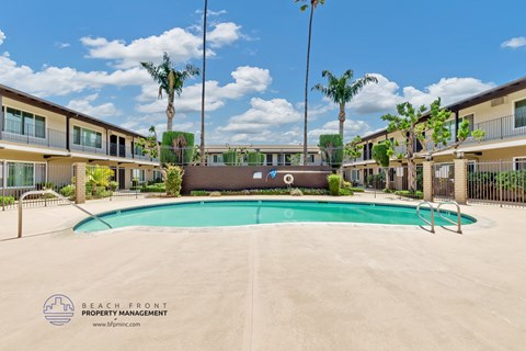 a resort style swimming pool with palm trees and apartments in the background