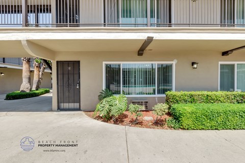 the entrance to a condo building with a driveway and a patio