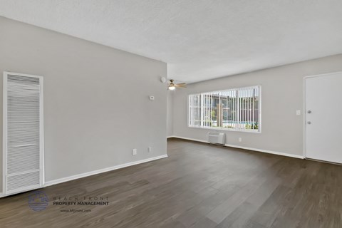 the spacious living room with wood flooring and a large window