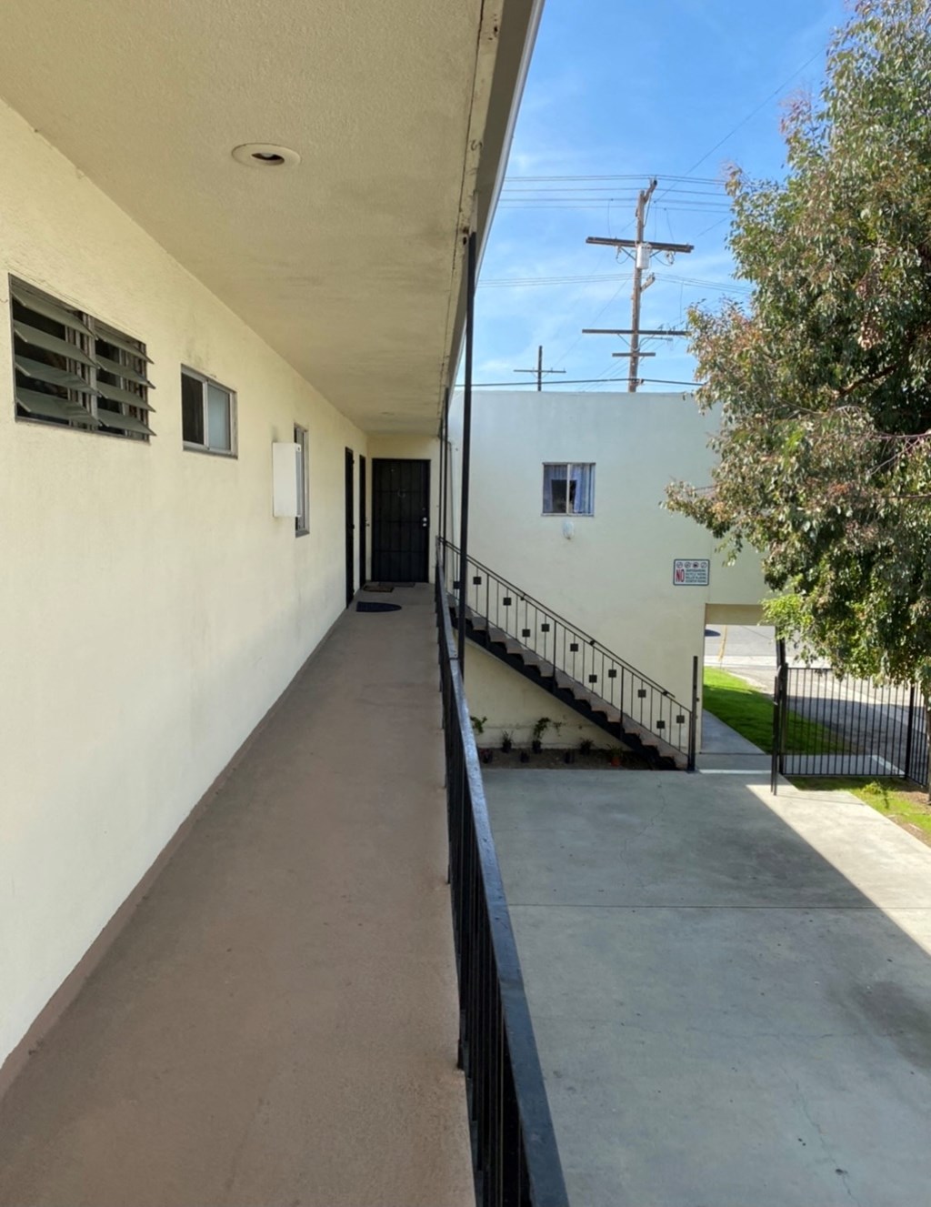 a balcony with a view of a white building and a tree