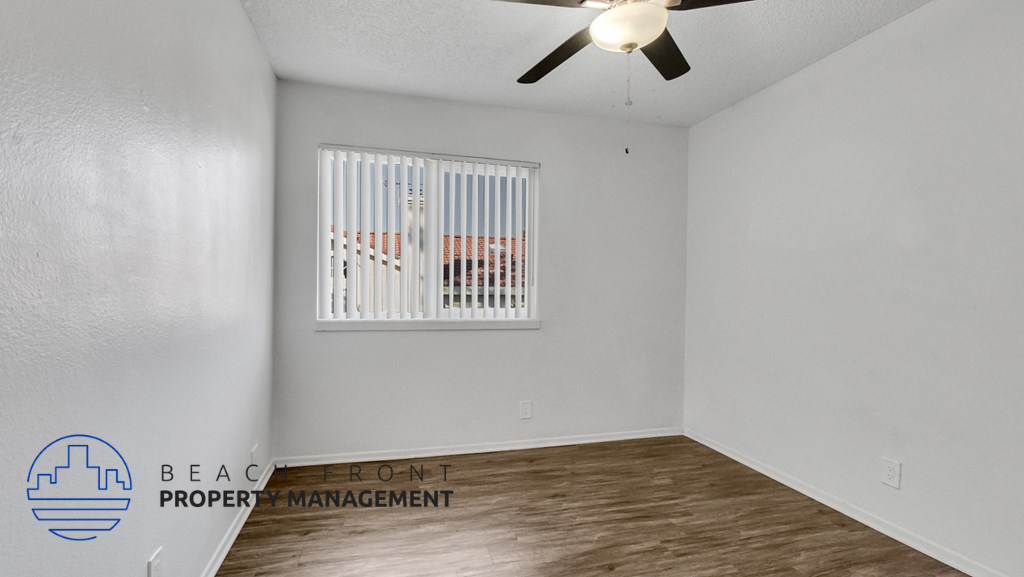 the spacious living room with a window and a ceiling fan