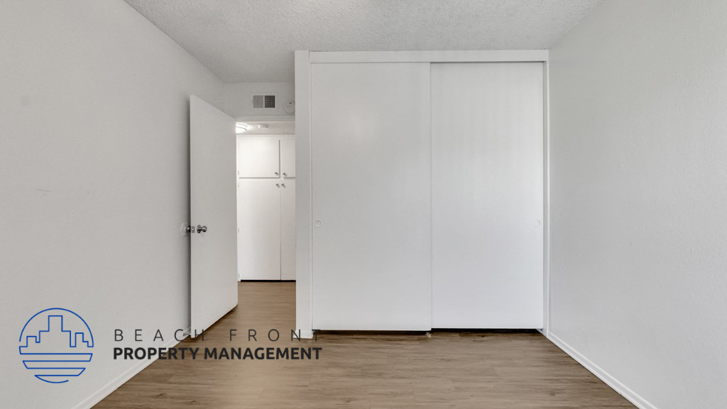 a bedroom with white walls and wood floors and a white closet