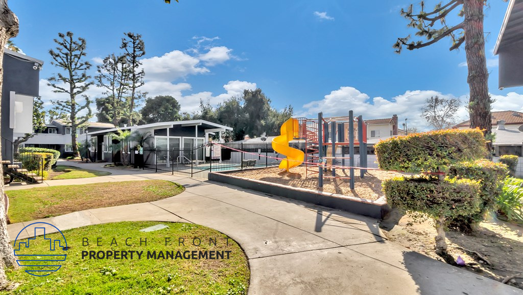 a playground with a yellow slide at the beach town property management