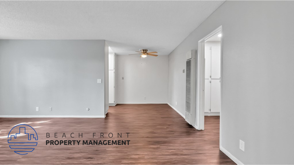 the spacious living room with hardwood flooring and a ceiling fan
