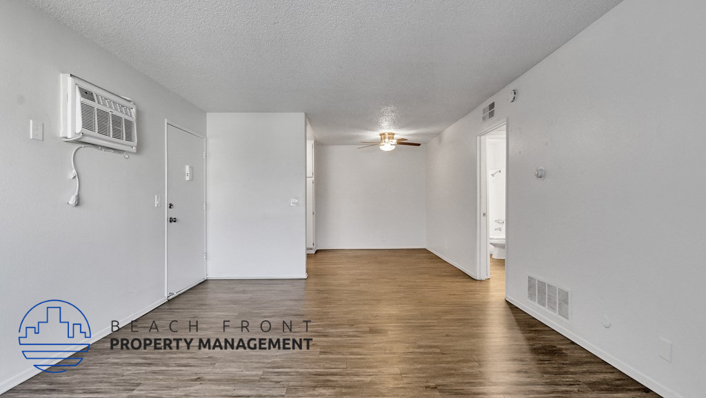 a spacious living room with white walls and wood flooring