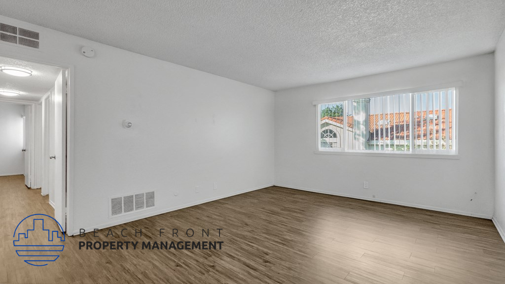 the living room of an apartment with wood flooring and a window