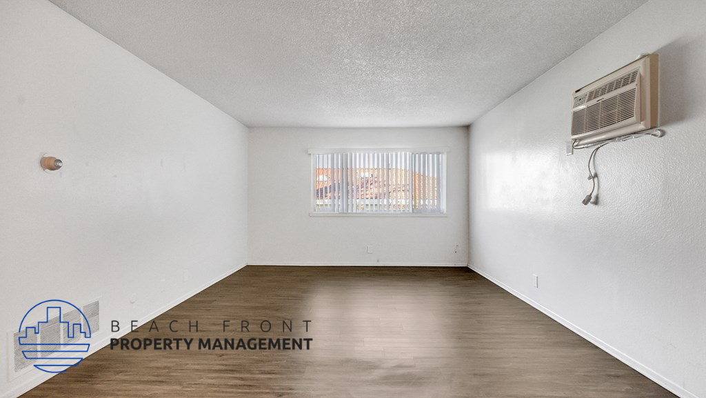 the spacious living room of this manufactured home has wood flooring and a window